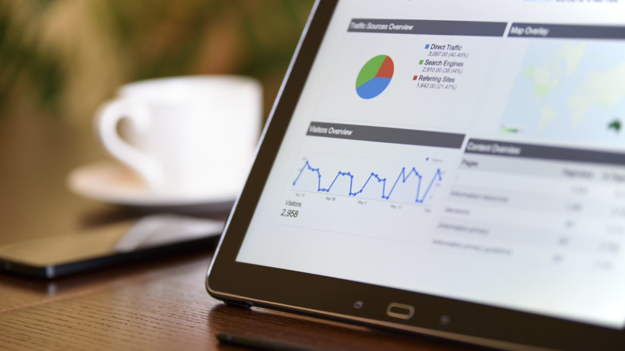 Charts and analytical data on the tablet screen with a cup of coffee and a telephone in the background